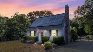 A house with a brick chimney, solar panels, and an American flag. - Cape Cod Family Escape w/ Pool, Game Room & Patio (Falmouth)