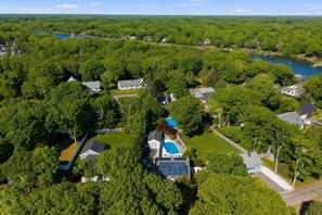 An aerial view of a residential area with houses, a swimming pool, and a solar panel installation. - Sun, Swim & Stay | Heated Pool + Firepit (Falmouth)