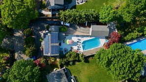 Vista aerea di una proprietà residenziale con piscina, pannelli solari e vegetazione circostante.