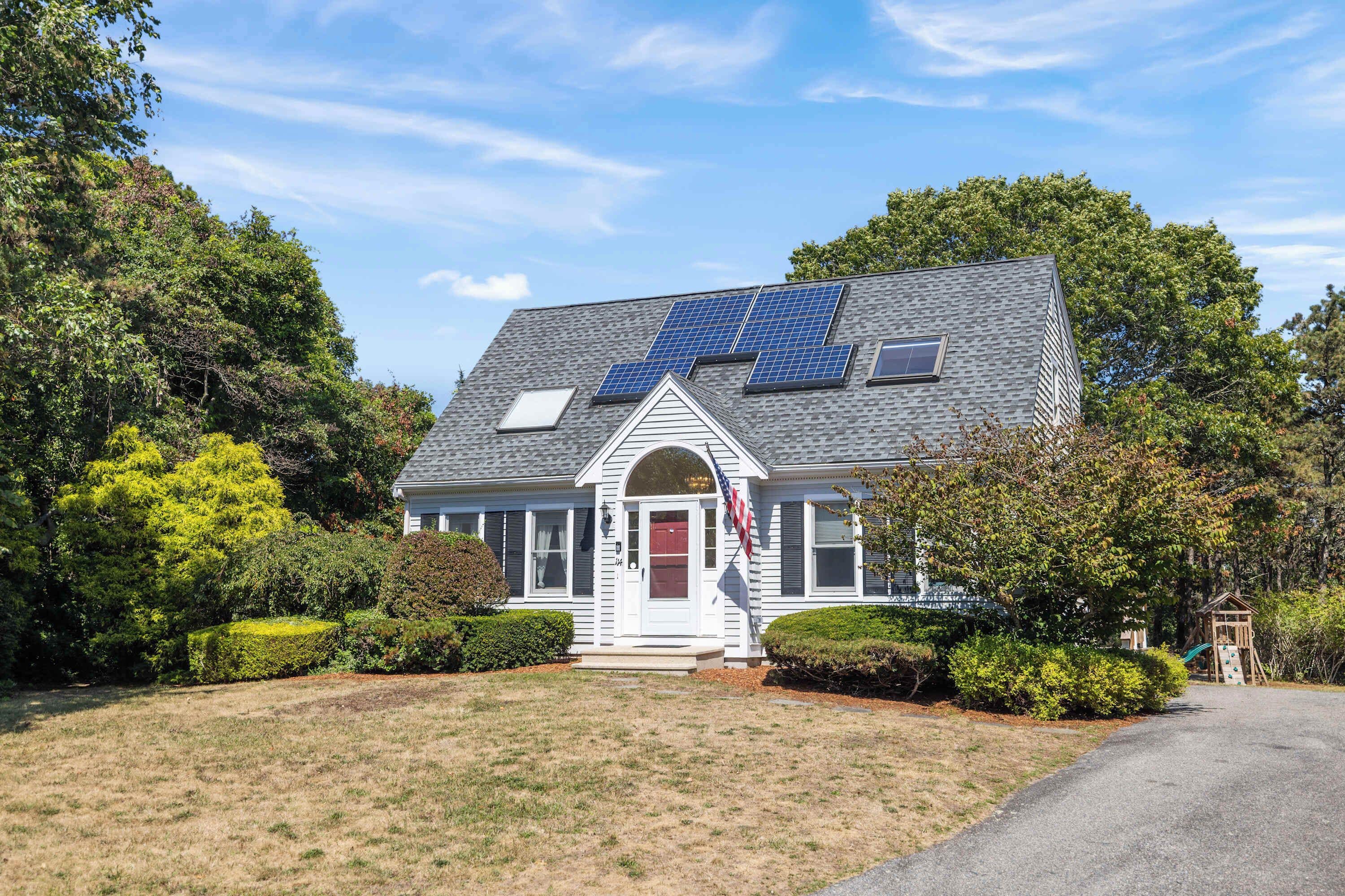 Ein Haus mit Solaranlage, rotem Eingang und einer Flagge.