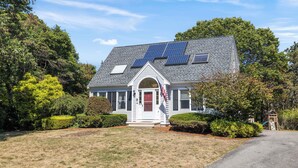 A house with solar panels, a red door, and a flag.