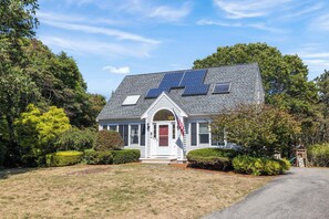 Une maison dotée de panneaux solaires, d’une porte rouge et d’un drapeau.
