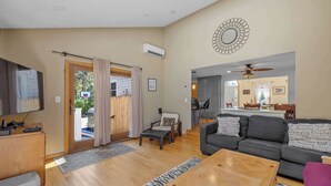 A living room with a sofa, a coffee table, a TV, and a door leading to an outdoor area.