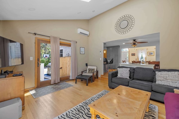 A living room with a sofa, a coffee table, a TV, and a door leading to an outdoor area.