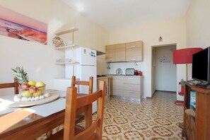Una cocina compacta con mesa, sillas, un refrigerador y un televisor.
