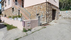 A two-story building with a stone facade, a metal staircase, and a paved driveway.
