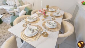 Een eettafel, gedekt met gouden en witte servies, omringd door luxe stoelen.