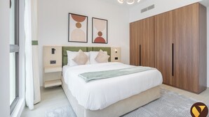 Een moderne slaapkamer met een bed, nachtkastjes, een kledingkast en twee kunstwerken aan de muur.