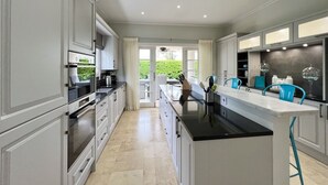 Een moderne keuken met witte kastjes, een zwart aanrecht eiland en uitzicht op een tuin.