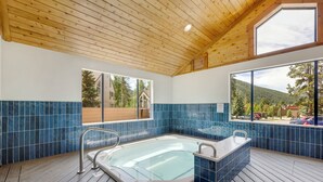 A spa area with a wooden ceiling, large windows, and a hot tub. - Mountain Comfort Steps From the Action (Keystone)
