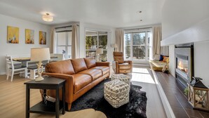 A modern living room with a leather sofa, a fireplace, and a dining area with a table and chairs. - Mountain Comfort Steps From the Action (Keystone)