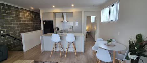 Una cocina moderna con armarios blancos, un refrigerador negro y una isla central con taburetes.