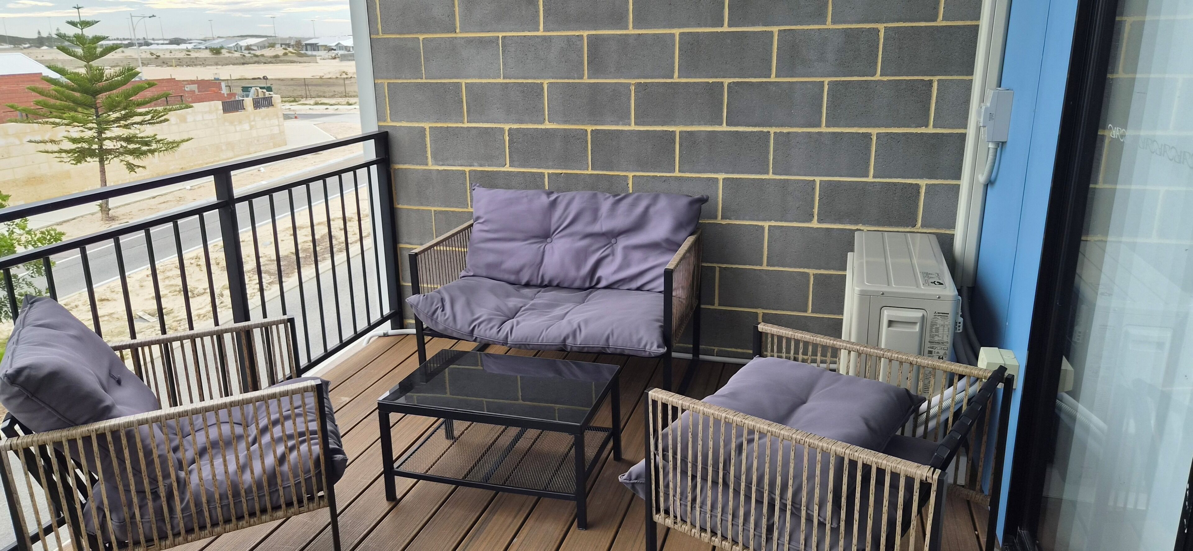 A balcony with a view of a construction site, featuring a chair and a small table.