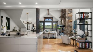 A modern kitchen with a large island, a stone fireplace, and a view of the outdoors.