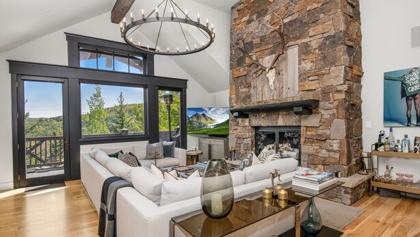 A modern living room with a stone fireplace, a large window with a scenic view, and a cozy seating area.