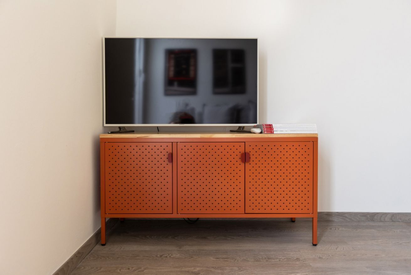 Ein Fernseher auf einer Holzeinrichtung mit gelochten Türen.