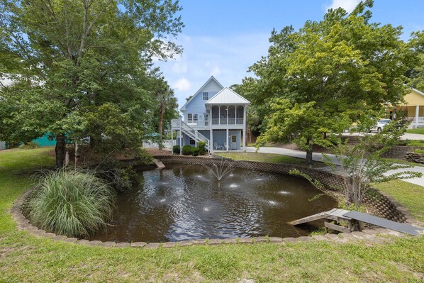 A house with a pond, surrounded by trees and a small deck.