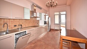 A modern kitchen with a dishwasher, stainless steel appliances, and a dining area with a wooden table and chairs.