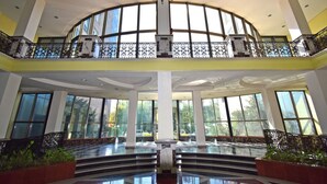 A spacious interior with a high ceiling, large windows, and a central staircase.