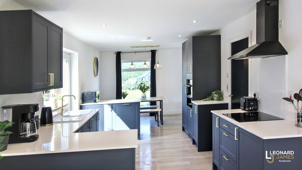 Una cocina moderna con armarios oscuros, una isla central y vistas al exterior.