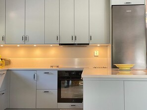 Eine Küche mit grauen Schränken, einem Edelstahlkühlschrank und einem eingebauten Backofen.