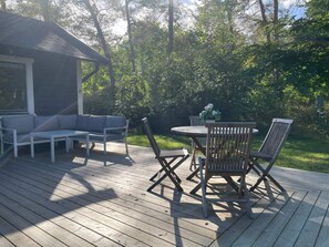 A wooden deck with a round table and chairs, a sofa, and a small shed. - 5 Star Holiday Home in Ystad (Ystad)