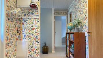 A hallway with patterned wallpaper, a globe on a shelf, and a wooden door.