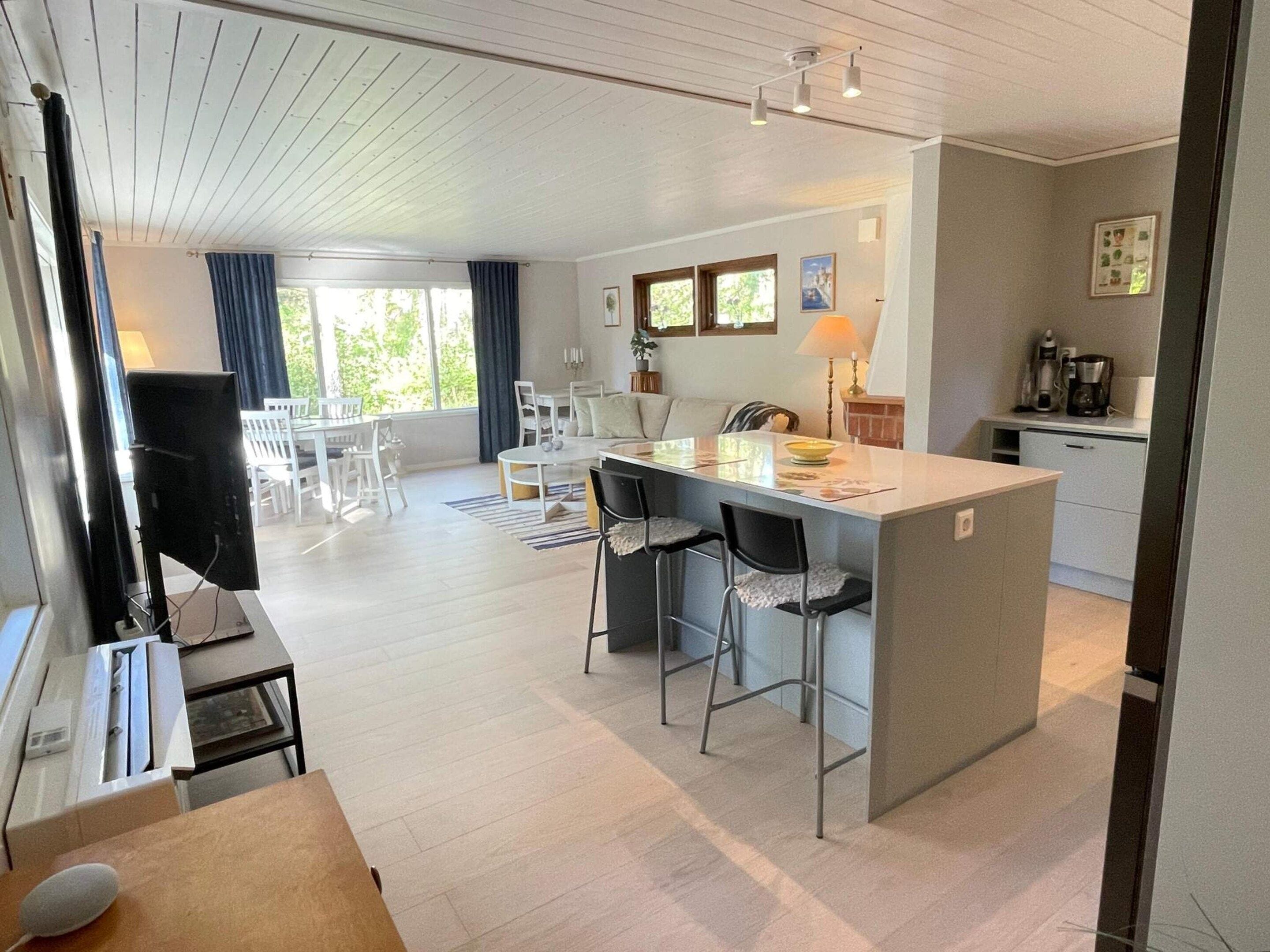 A modern kitchen with a central island, bar stools, and a dining area with a table and chairs.