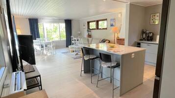 A modern kitchen with a central island, bar stools, and a dining area with a table and chairs.