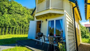 Ein zweistöckiges Haus mit einem Balkon, einem Grill und einem Tisch mit Stühlen auf der Terrasse.