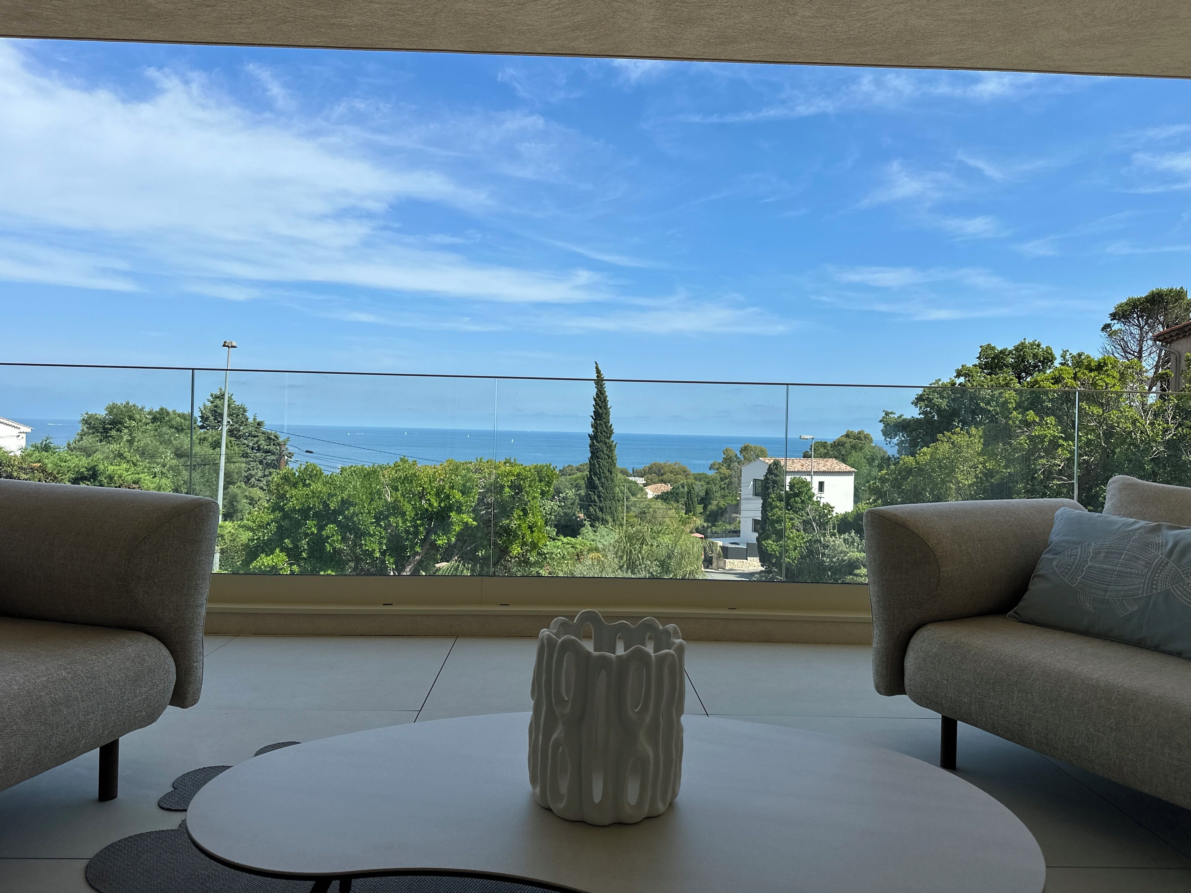 A balcony with a view of the sea, two sofas, and a central table.