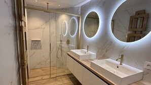 A modern bathroom with two sinks, a glass shower enclosure, and marble walls. - Villa Les Issambres, infinity pool, sea view (Roquebrune-sur-Argens)