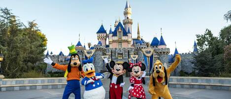 A group of animated characters in front of a castle-like building.