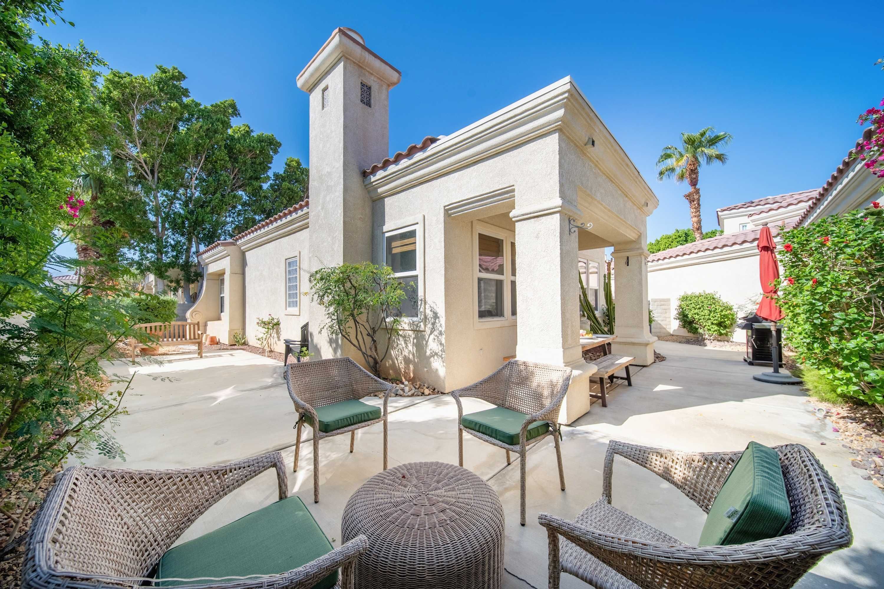 A house with a patio area featuring wicker furniture and a small tower structure.