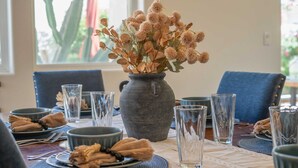 Ein Esstisch mit Tellern, Schüsseln und einer Vase mit Trockenblumen.