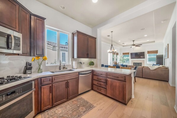 A modern kitchen with dark wood cabinets, stainless steel appliances, and a large island.