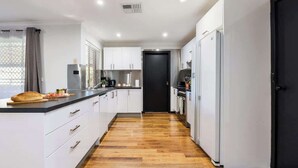 Une cuisine moderne avec des meubles blancs, un réfrigérateur noir et un plancher en bois.