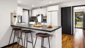 Une cuisine moderne dotée d’un îlot central, de tabourets de bar et offrant une vue sur l’espace extérieur.