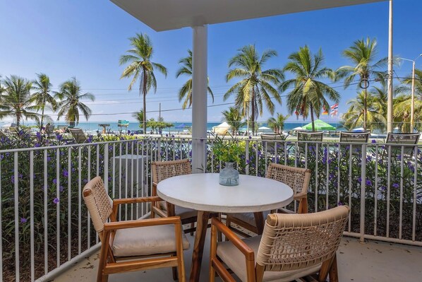 Ein Balkon mit Korbmöbeln und Blick auf den Strand und Palmen.