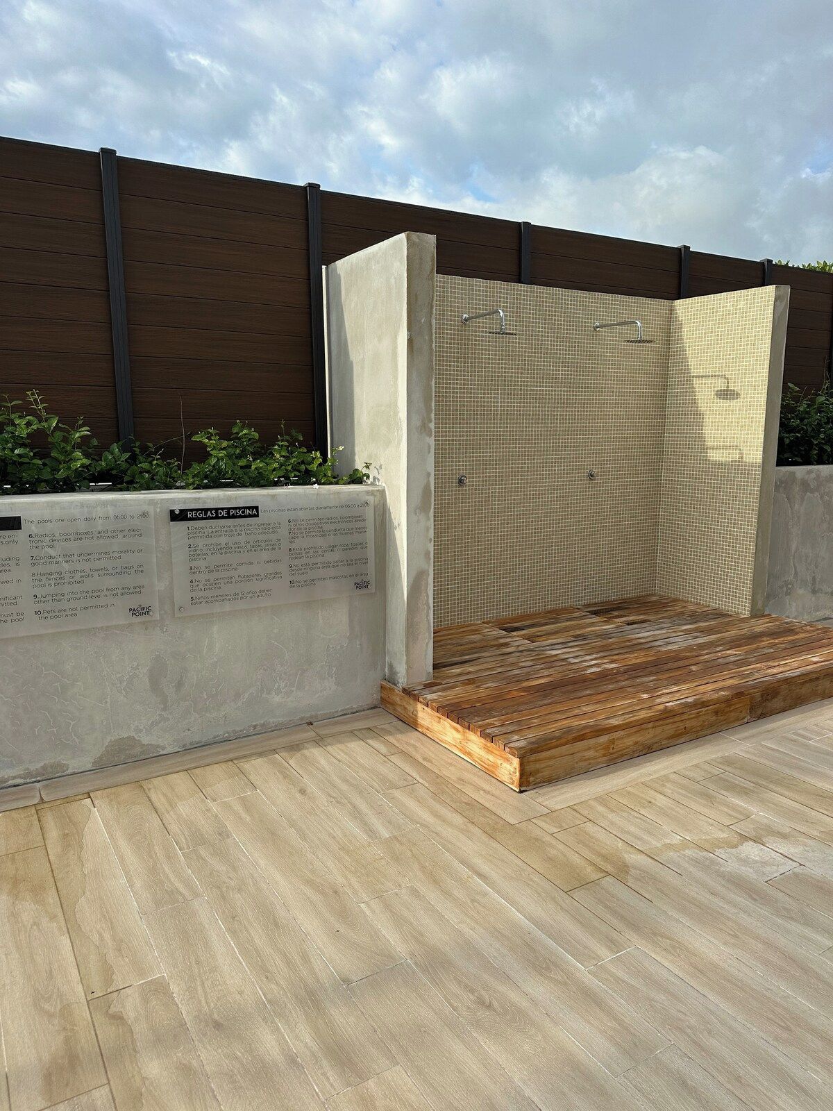 Une terrasse en bois avec un espace piscine, comprenant un banc en bois et un mur recouvert de carreaux.