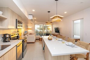 A modern kitchen with a central island, built-in appliances, and pendant lighting. - Luxury Ocean Front Condo (Jaco Beach)