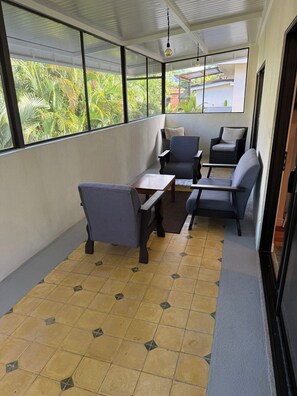 A balcony with seating, a view of greenery, and a tiled floor. - Jaco Beach House (Jaco)