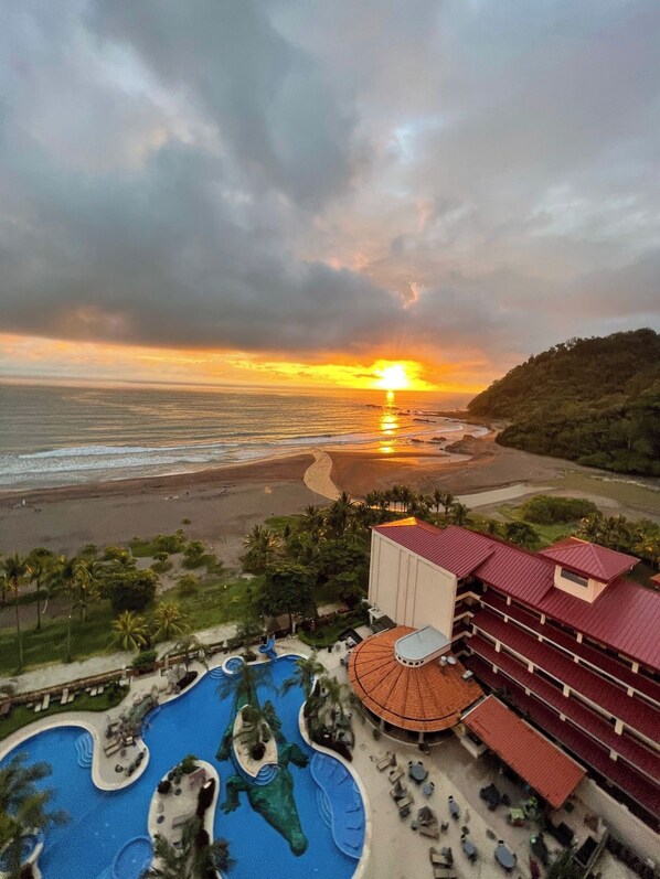 Ein Resort mit Poolbereich, Strand und Blick auf den Sonnenuntergang.