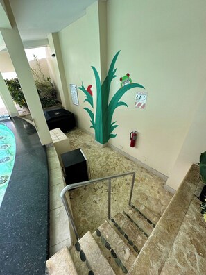 A hotel lobby with a pool, a fire extinguisher, and a staircase. - Oceanfront Property Condo - 3 bedroom (Jaco)
