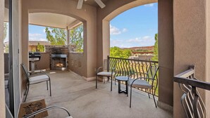 A covered outdoor area with a ceiling fan, a stone fireplace, and a view of the surrounding landscape. - The Overlook at Coral Springs (Hurricane)