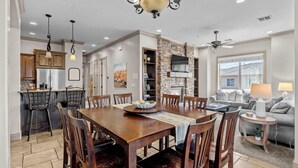 A spacious dining area with a wooden table and chairs, a stone accent wall, and a fireplace. - The Overlook at Coral Springs (Hurricane)