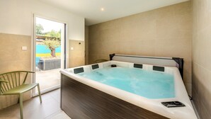 A modern bathroom with a hot tub, a chair, and a view of a swimming pool. - Welcome to Marius and Augustin's Home (Goulven)