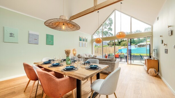 A dining area with a wooden table, chairs, and hanging lights. - Welcome to Marius and Augustin's Home (Goulven)