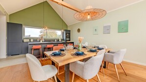 A modern kitchen with a dining area, wooden ceiling beams, and a large window. - Welcome to Marius and Augustin's Home (Goulven)
