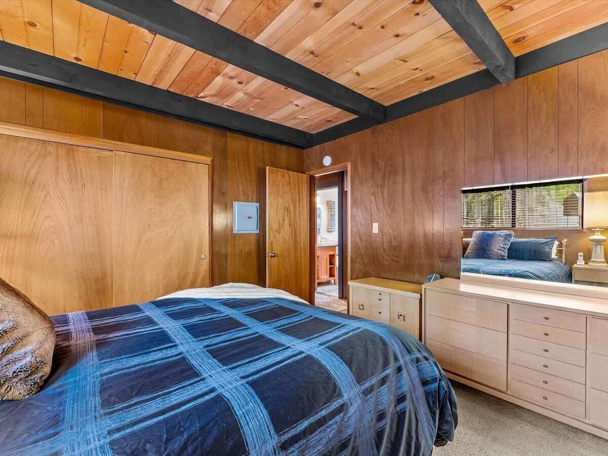 Une chambre à coucher avec un lit, une commode et une fenêtre équipée de stores.